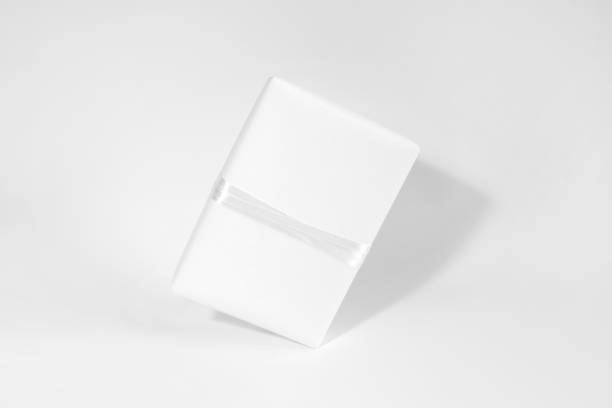istock One gift box in white wrapping paper with white rope on white table. Isolated wrapped gift mock up with ribbon. 1358935043