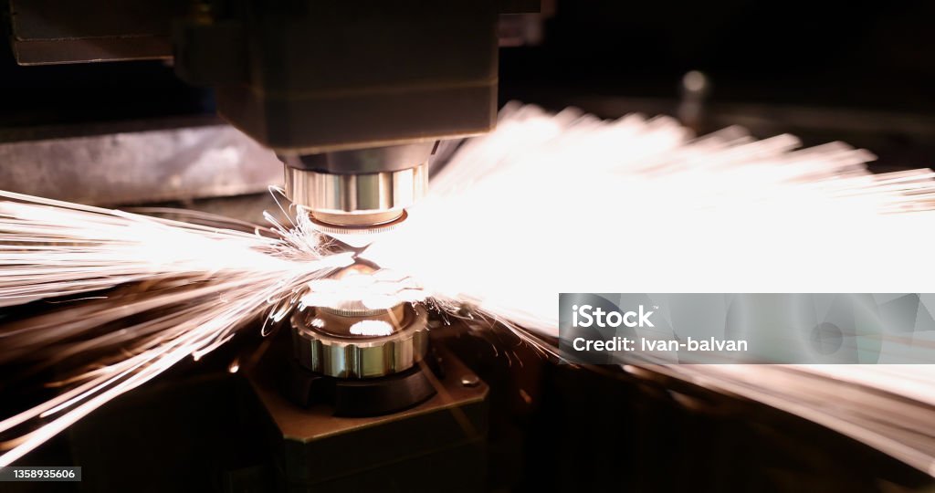 Neon sparks fly of machine head for metal processing laser metal Close-up of neon sparks fly of machine head for metal processing laser metal. Cutting machine and metal plate. Manufacturing, production, factory concept Industry Stock Photo