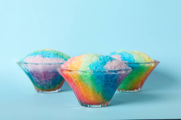 istock Rainbow shaving ice in glass dessert bowls on light blue background 1358937527