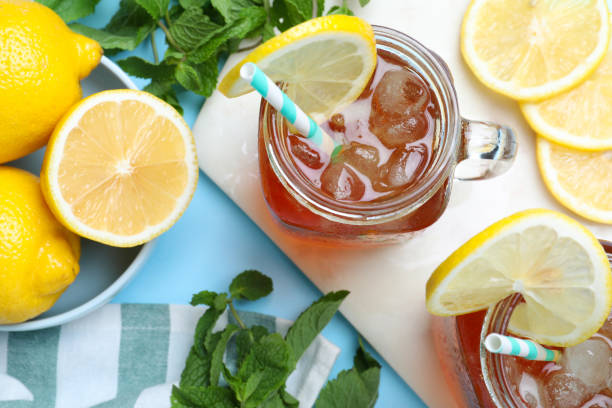 istock Delicious iced tea with lemon and mint on light blue background, flat lay 1358940454