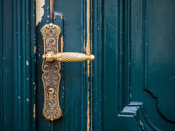 Photo of close up view on brass door knob and old green wooden door