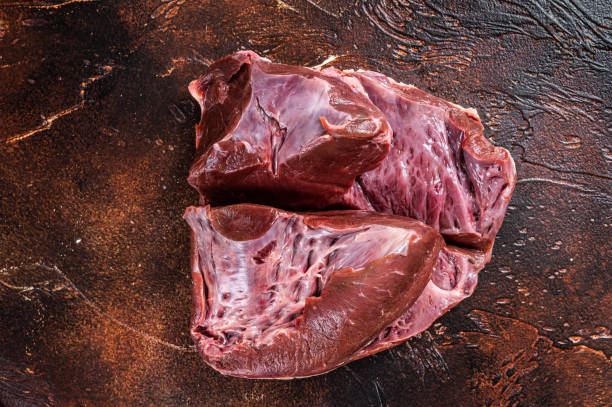 istock Cut Beef or veal raw heart on a butcher table. Dark background. Top View 1358941865
