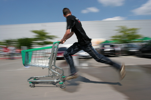 A man running with a shopping cart. Motion blur.