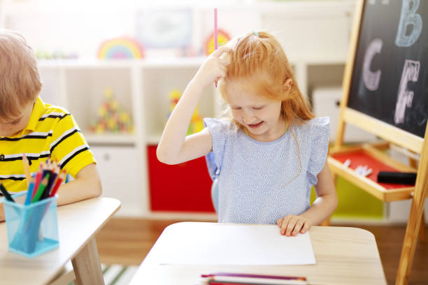 istock Cute girl sitting in the classroom and thinking over a task 1358945337
