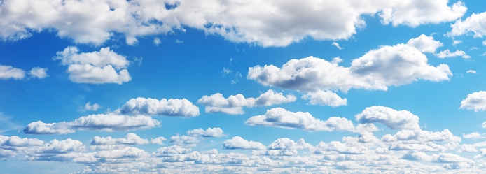 Blue sky with soft white clouds in sunny day. Panoramic view of the beautiful fluffy cloudscape.