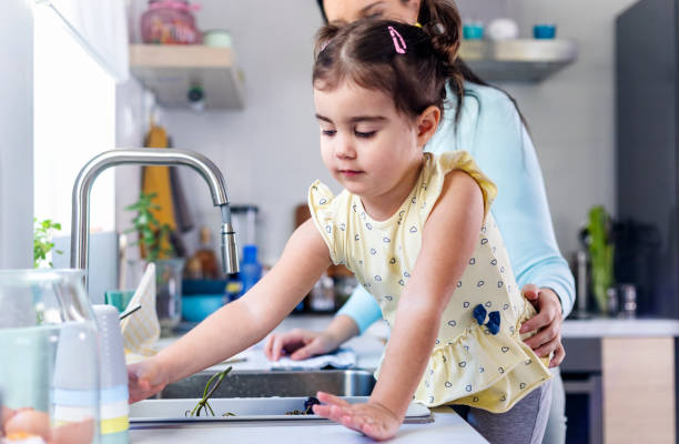 istock Mother and daughter washing dishes 1358946970