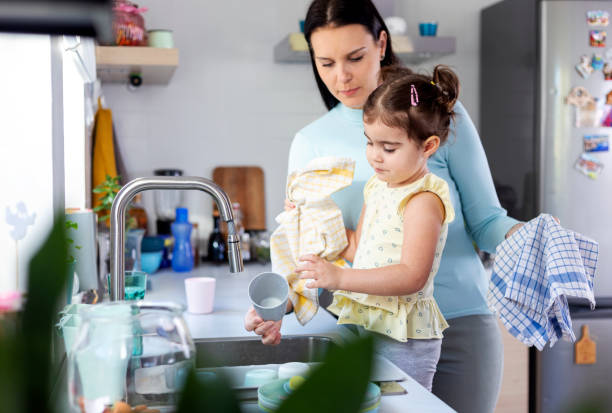 istock Mother and daughter washing dishes 1358946981