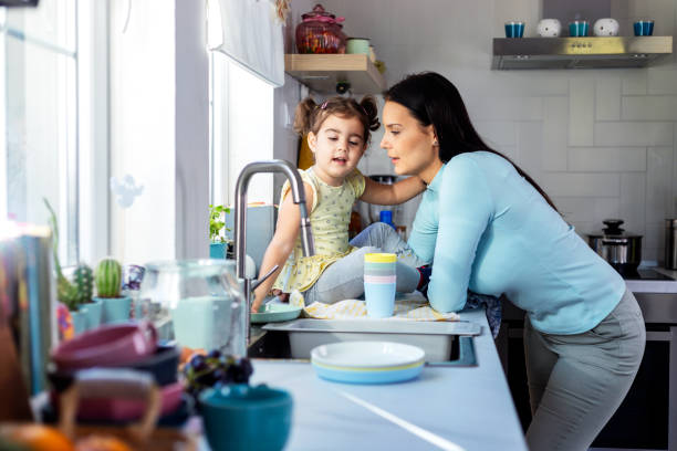 istock Mother and daughter washing dishes 1358947004