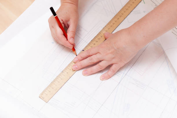 istock Female hands do the layout of the sewing pattern on paper 1358947124