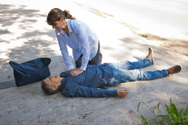 женщина оказывает первую помощь пожилому мужчине - human hand help pain heart attack стоковые фото и изображения