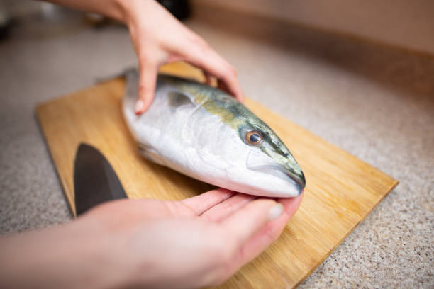 istock Female cooking raw fish in the kitchen 1358947296
