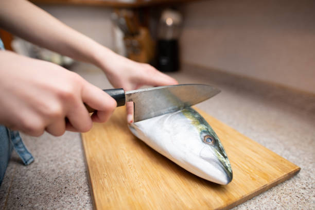 istock Female cooking raw fish in the kitchen 1358947299