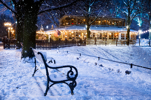 Winter view of a bench on the viewing terraces  on Walach Chrobrego, a pub with Christmas decorations in the background, Szczecin , Poland