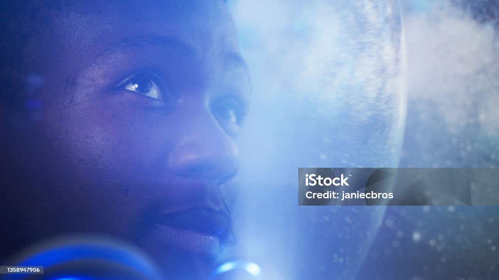 Looking for New Earth. African ethnicity man exploring Space, travelling through bright cosmic dust Young man looking at breathtaking view. Space reflecting in helmet visor. Close up on eyes Astronaut Stock Photo