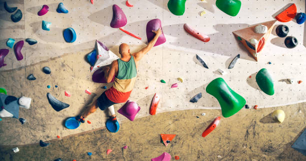 istock Strong Experienced Rock Climber Practicing Solo Climbing on Bouldering Wall in a Gym. Man Exercising at Indoor Fitness Facility, Doing Extreme Sport for His Healthy Lifestyle Training. Shot from Back. 1358948280