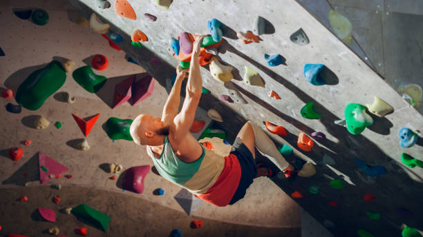 istock Strong Experienced Rock Climber Practicing Solo Climbing on Bouldering Wall in Gym. Man Exercising at Indoor Fitness Facility, Doing Extreme Sport for His Healthy Training. Lifestyle Portrait. 1358948380