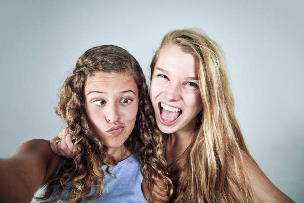 바보 같은 셀카를 찍는 두 명의 젊은 여성, 아마 소셜 미디어 - making a face humor puckering cross eyed 뉴스 사진 이미지