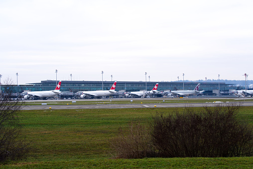 Terminal building named Dock Midfield with parked long distance airplanes on a foggy winter day. Photo taken December 12th, 2021, Zurich, Switzerland.