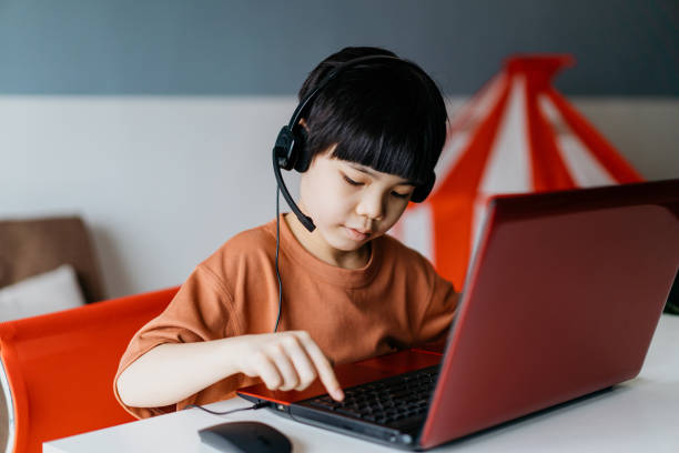istock Young asian boy using laptop at home 1358950973
