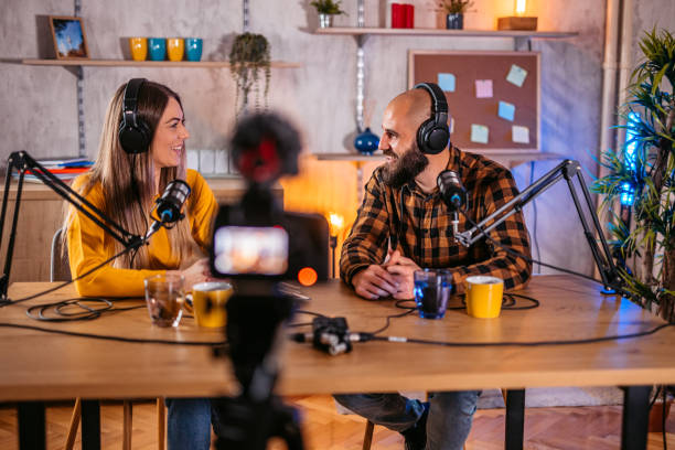istock Two hosts in headphones recording podcast in broadcasting 1358951127