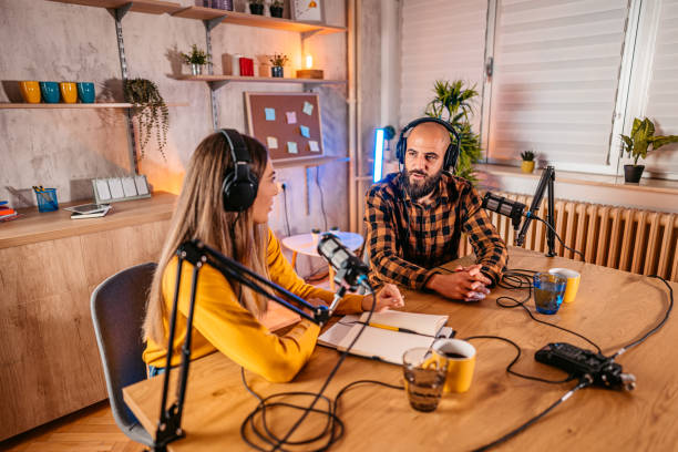 istock Two hosts in headphones recording podcast in broadcasting 1358951163