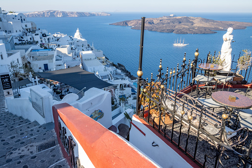 Palia Kameni Cocktail Bar in Firá on Santorini in South Aegean Islands, Greece, with a garden statue visible andthe Church of St Minas in the background