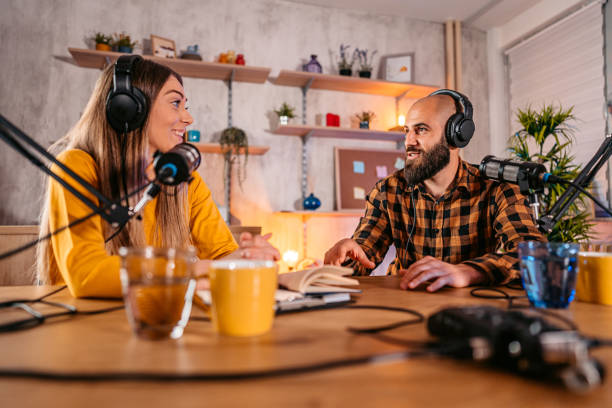 istock Two hosts in headphones recording podcast in broadcasting 1358951259