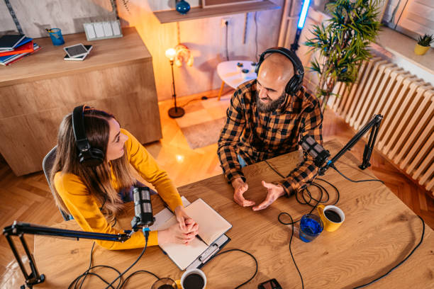 istock Two hosts in headphones recording podcast in broadcasting 1358951361