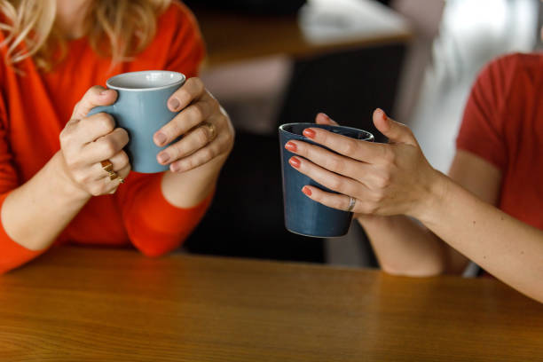 istock Two women holding coffee cups and chatting during coffee break 1358951400