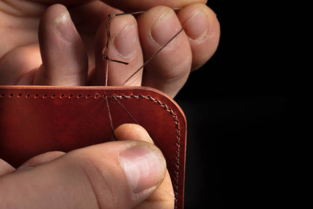 istock Making leather wallets. The hands of the master sew a leather product. 1358952150