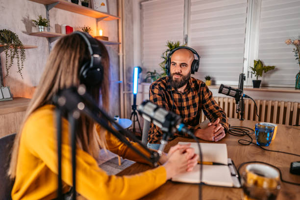 istock Two hosts in headphones recording podcast in broadcasting 1358952264