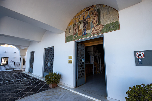 The entrance to the Orthodox Metropolitan Cathedral of Firá in Santorini on South Aegean Islands, Greece, with a religious image visible.