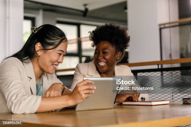 Two Businesswomen Watching A Funny Video On Digital Tablet Stock Photo -  Download Image Now - iStock
