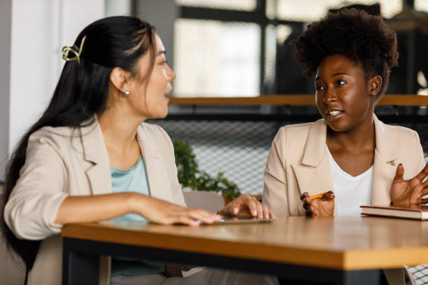 istock Two young businesswomen discussing ideas while co-working on a project 1358954352