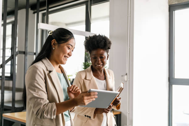 istock Two businesswomen walking through the office, reviewing data on digital tablet 1358954354