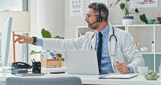 istock Shot of a mature doctor sitting alone and using his computer while wearing a headset during an online consultation 1358954972