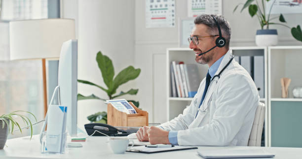 istock Shot of a mature doctor sitting alone and using his computer while wearing a headset during an online consultation 1358954988