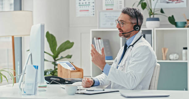 istock Shot of a mature doctor sitting alone and using his computer while wearing a headset during an online consultation 1358954992
