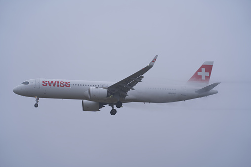 Swiss airplane landing at Zürich Airport on a foggy winter day. Photo taken December 12th, 2021, Zurich, Switzerland.