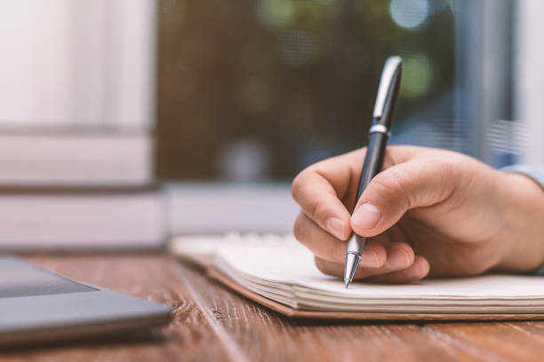 istock woman holding a pen sitting on a desk writing 1358956108