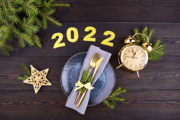 festive table setting. happy new year 2022. plate, silverware, fir branches, golden alarm clock. - new years eve christmas paper christmas fir tree imagens e fotografias de stock