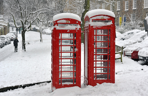 Two classic vintage red public telephone boxes in London - in the snow