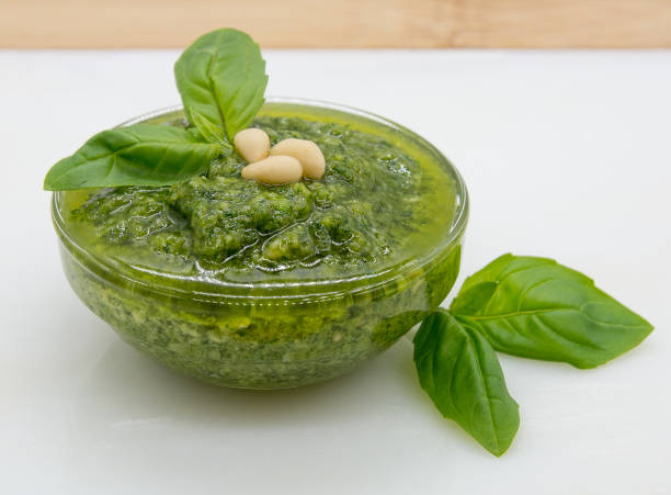 istock Pesto sauce in a glass container with basil and pine nuts on top 1358956637