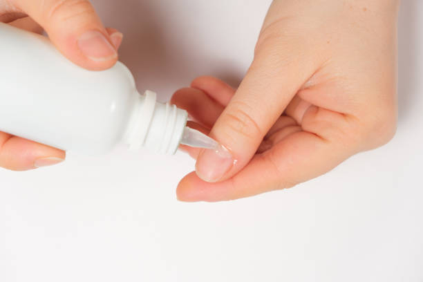 istock Woman applies cuticle remover to nails on white background 1358958621
