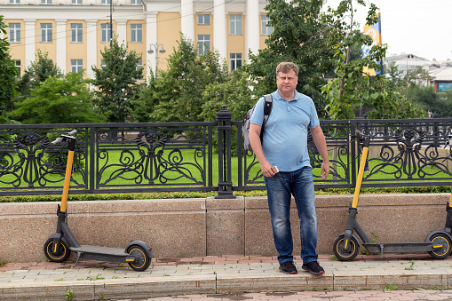 An adult man rents an electric scooter through smartphone application.