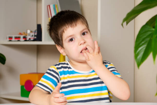 Preschool boy 4 years old bites his nails looking at the camera Preschool boy 4 years old bites his nails looking at the camera. nail biting stock pictures, royalty-free photos & images