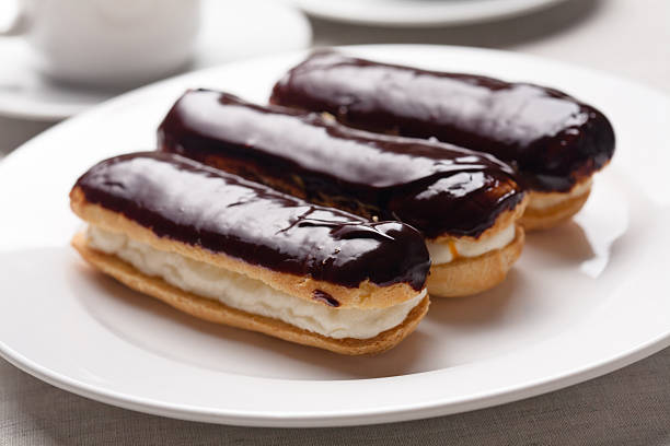 3 chocolate cream eclairs on a white plate