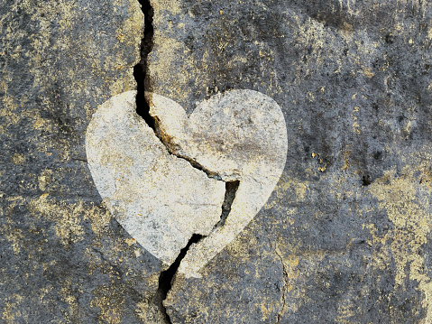 Love symbol on a cracked grungy wall surface