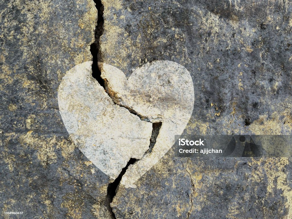 Love symbol on a cracked grungy wall surface Broken Heart Stock Photo