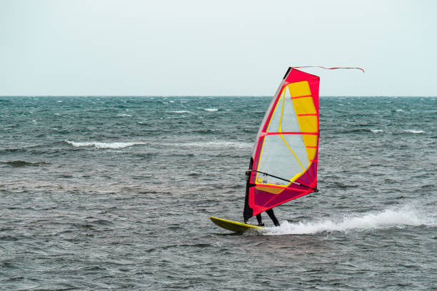 istock Orange and Red Windurf Riding the Waves in a Choppy Sea 1358960678